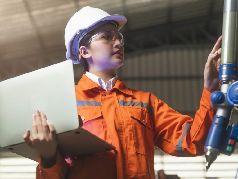 asian female engineer specialist with Measuring machine with a manipulator arm.Three-dimensional coordinate measurement. Check sizes. 3D check of the sizes of parts. CMM after machining process
